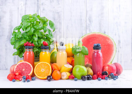 Viele verschiedene Früchte und Beeren und Säfte in Kunststoffflaschen. Wassermelonen, Bananen, applcsin, Heidelbeeren, Erdbeeren, Basilikum auf einem weißen Hintergrund. Vitamin- und gesundes Essen. Detox. Platz kopieren Stockfoto