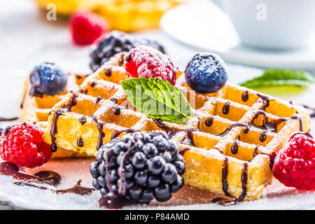 Frische Waffeln mit Schokolade Sirup Beeren Zucker Pulver und Minzeblättchen. Stockfoto