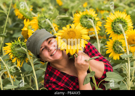 Junge schöne Bauernmädchen examing Ernte von Sonnenblumen in Feld im Sommer Stockfoto