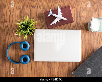 Reisender Geschäftsmann Draufsicht auf hölzernen Schreibtisch Konzept Bild, Kopfhörer, Topf von Gras, Buch Stockfoto