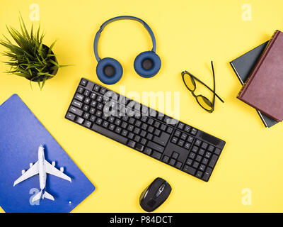 Reisender Geschäftsmann Blick von oben auf seinem gelben Desktop, Kopfhörer, Zwischenablage, Topf von Gras Stockfoto