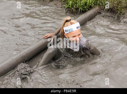 Biddinghuizen, Niederlande - 23. Juni 2018: Kind während einer mudrun (mudraise) im Schlamm und im Wasser klettern einen Baumstamm. Stockfoto