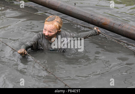 Biddinghuizen, Niederlande - 23. Juni 2018: Das Kind während ein Schlamm laufen (mudraise, Nächstenliebe) in den Schlamm und in das schwarze Wasser. Stockfoto