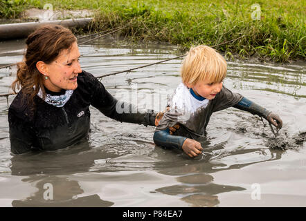 Biddinghuizen, Niederlande - 23. Juni 2018: Frau helfen Kind während ein Schlamm laufen (mudraise) im Schlamm und im Wasser. Stockfoto