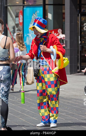 Street Entertainer gekleidet wie ein Clown verkaufen Lustig geformte Ballons, um die Öffentlichkeit in Liverpool, Großbritannien. Stockfoto