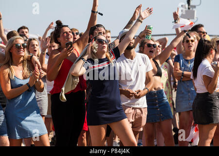 England Fußball-Fans der WM-Viertelfinale England v Schweden auf einem riesigen TV-Bildschirm am Strand von Brighton in England das Halbfinale erreichen. Großbritannien Stockfoto