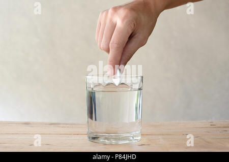 Frau Brausetablette in einem Glas Wasser auf hölzernen Tisch Stockfoto