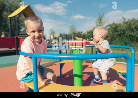 Bild des freudigen Geschwister Spaß am Karussell im Freien. Spaß auf dem Spielplatz Konzept Stockfoto