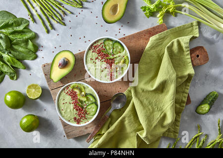 Grüne smoothies von Avocado mit Gurke, Kiwi und Flachs in eine Platte auf einem Holzbrett auf grauem Beton Hintergrund. Gesunde Ernährung Stockfoto