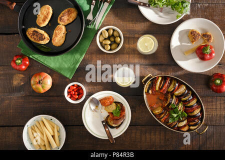 Verschiedene vegetarische Speisen auf Holztisch. Ratatouille, Kichererbsen Koteletts, Limonade und verschiedene Snacks, Ansicht von oben. Vegetarisches Abendessen Tabelle Konzept Stockfoto