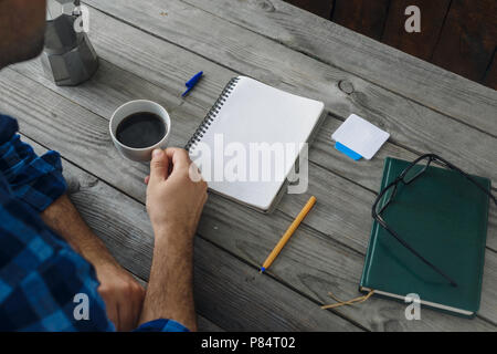 Mann mit Notepad und Tasse Kaffee arbeiten im Home Office Stockfoto