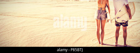 Ansicht der Rückseite des Paar hält Surfboards beim Stehen am Strand Stockfoto