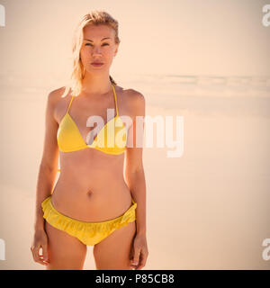 Porträt der jungen Frau im gelben Bikini am Strand Stockfoto