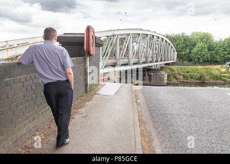 09 - Juli 2018 - Männliche Fußgängerzone lehnt sich gegen eine Wand und beobachtet, wie Stockton Heide Swing Bridge schließt nach einem Schiff entlang der Manchester Shi bestanden hat Stockfoto