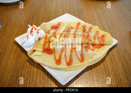 Pfannkuchen mit Erdbeer Sirup und Sahne in eine quadratische Platte Stockfoto