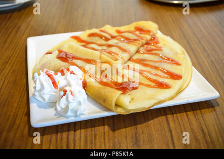 Pfannkuchen mit Erdbeer Sirup und Sahne in eine quadratische Platte Stockfoto