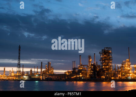 Industrie Raffinerie bei Sonnenuntergang mit bewölktem Himmel, Erdöl Fabrikgebäude auf Wasser Küste in der Dämmerung. Stockfoto