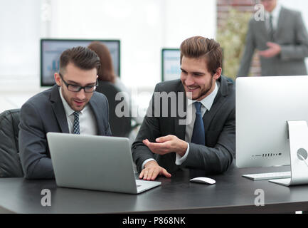 Freundliche Kollegen Spaß am Schreibtisch mit Laptop sitzen Stockfoto