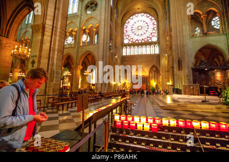 PARIS, Frankreich, 1. Juli 2017: Menschen Beleuchtung die Kerzen im Kirchenschiff Altar von Notre Dame von Paris gotische Kathedrale. Glasmalerei Rose windows auf der Oberseite. Stockfoto