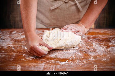 Weibliche Hände vorbereiten Teig für Pizza auf dem Tisch closeup Stockfoto