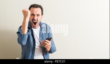 Ältere Menschen mit Smartphone genervt und frustriert schrie mit Zorn, verrückt und schreien mit erhobener Hand, Wut Konzept Stockfoto