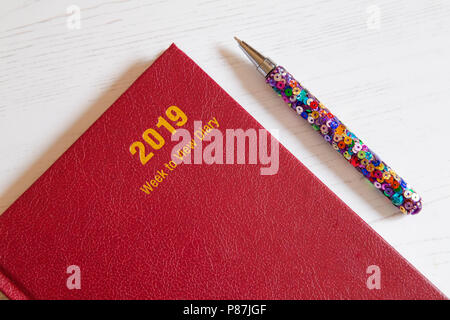 Ein rotes 2019 Schreibtisch Tagebuch mit einem Stift. Stockfoto