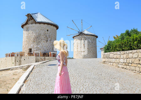 Die Windmühlen von alacati und die Dame in rosa Sie beobachten in Cesme, Izmir, Türkei Stockfoto