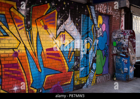 Straße in New York City mit einem bunten urban Graffiti im East Village in Manhattan eine Bank Geldautomat mit Aufkleber und eine Flasche Stockfoto