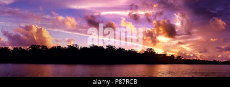 Eine markante inspirational Rot/rosa gefärbte bewölkt Sonnenaufgang Marine über Meer Wasser mit Wasser Reflexionen. In Queensland, Australien gefangen. Stockfoto