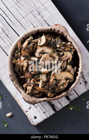 Hohe Betrachtungswinkel und einer braunen Steingut Schale mit einige gekochte gemischte Pilze, wie z. B. gemeinsame Champignons, Austernpilze und Shiitake, auf einem weißen Tropfen Stockfoto