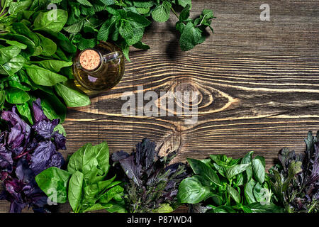 Auswahl an frischen Kräutern auf Holz- Hintergrund. Frisch geerntete Kräuter wie Basilikum, Rucola. Ansicht von oben. Kopieren Sie Platz. Stockfoto