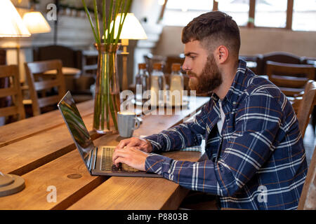 Young Professional beim Surfen im Internet auf seinem Laptop in einem Café Stockfoto