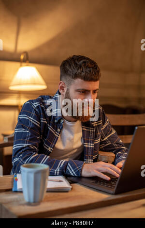 Young Professional beim Surfen im Internet auf seinem Laptop in einem Café Stockfoto