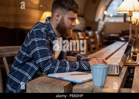 Young Professional beim Surfen im Internet auf seinem Laptop in einem Café Stockfoto