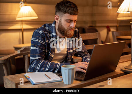 Young Professional beim Surfen im Internet auf seinem Laptop in einem Café Stockfoto