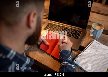 Zugeschnittenes Bild des jungen Mannes über Net chatten - buchen Sie während der Pause im Café, Männer sitzen vor offenen Laptop mit leeren Kopie Raum angezeigt. Stockfoto