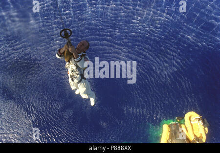 Astronauten Charles Conrad jr. ist bis zu einer Marine Helikopter hochgezogen, während Astronauten L. Gordon Cooper jr. in eine Rettungsinsel unten nach der Wasserung der Gemini-5 wartet Stockfoto