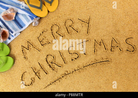 Frohe Weihnachten Nachricht in Sand geschrieben auf einem sonnigen Strand, Weihnachten Strand Ferienhäuser Konzept Stockfoto