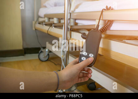 Die Hand des asiatischen Frau Jetzt drücken Sie auf der Fernbedienung die Höhe der Krankenhausbett anzupassen. Johns in ein Krankenhausbett verstellbares Bett. Stockfoto