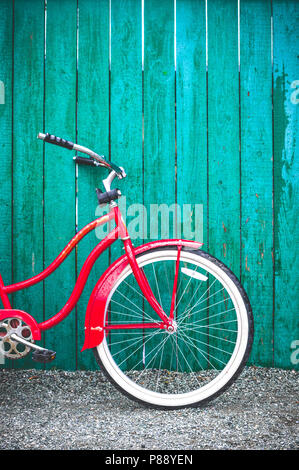 Red vintage altmodische Single Speed Fahrrad mit weißen Reifen lehnte sich gegen eine grün gestrichenen Holzzaun. British Columbia, Kanada. Stockfoto