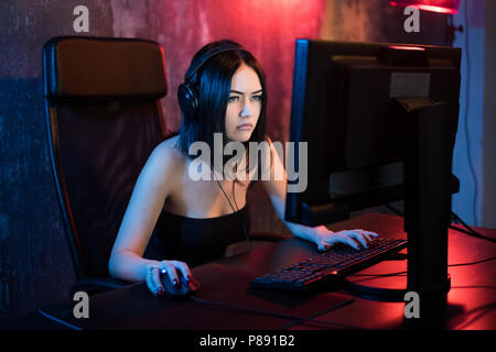 Professionelle girl Gamer spielt in MMORPG oder Strategie Spiel auf Ihrem Computer. Sie ist die Teilnahme an Online Cyber Games Turnier, spielt zu Hause oder im Internetcafé. Sie trägt Gaming Headset Stockfoto