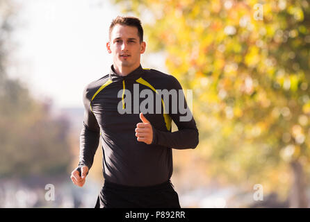 Hübscher junger Mann Sportkleidung tragen und läuft im Wald am Berg im Herbst Stockfoto