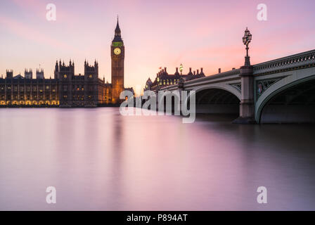 Magenta Sonnenuntergang über den Big Ben und die Houses of Parliament in London, einschließlich die Westminster Bridge spiegelt sich in den glatten Wasser der Themse Stockfoto