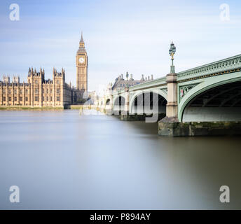 Big Ben und die Houses of Parliament in London, einschließlich die Westminster Bridge spiegelt sich in den glatten Wasser der Themse an einem sonnigen Tag Stockfoto