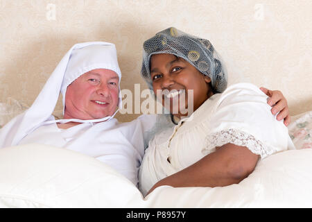 Reifes Paar im Vintage Kleidung im Bett lächeln Stockfoto