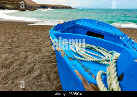 Einen alten blauen Boot mit einer Spule von Seil auf der schwarzen vulkanischen Strand Stockfoto