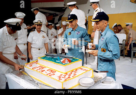 Gemini-12 Astronauten James A. Lovell Jr. (links), und Edwin E. Aldrin Jr. (rechts), Pilot, essen ein Stück Kuchen präsentiert die beiden Astronauten von Besatzungsmitgliedern des Prime recovery Schiff, die USS Wasp Stockfoto