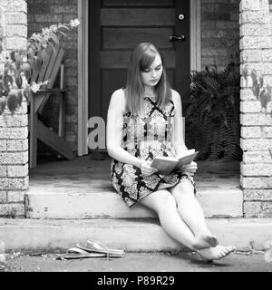 Junge Frau auf Stoop lesen Buch sitzen in Schwarz und Weiß Stockfoto