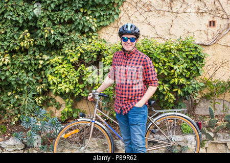 Glückliche junge männliche halten bycycle Hintergrund grün Garten Stockfoto