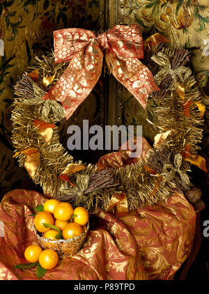 In der Nähe von Gold lametta Kranz mit metallischen Bug oben Schale von Orangen gebunden Stockfoto